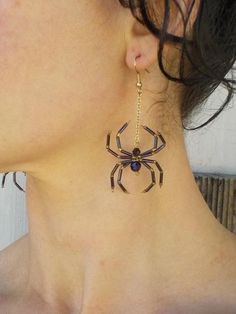 a close up of a woman's neck wearing spider earrings