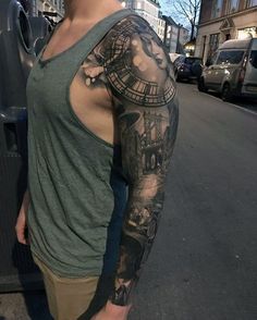 a man with a clock tattoo on his arm standing in front of a bus stop