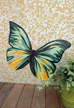 a green potted plant sitting on top of a wooden floor next to a butterfly