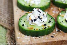 cucumber slices topped with whipped cream and sprinkles on a cutting board