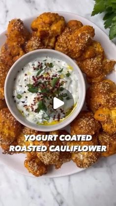 a white plate topped with tater tots covered in ranch sauce and garnished with parsley