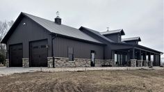 a large black barn with two garages on each side