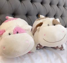 two stuffed animals sitting on top of a bed next to each other in front of a gray headboard