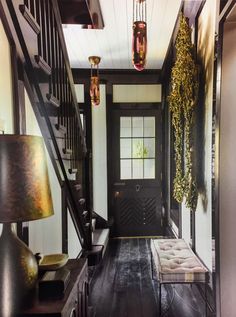 the entryway is decorated in black and white with gold accents on the door, chandeliers hanging from the ceiling, and an upholstered bench