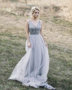 a woman wearing a gray dress standing in the grass