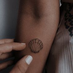 a woman's arm with a shell tattoo on the left side of her arm