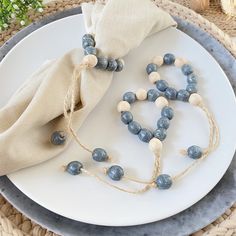 a white plate topped with blue beads next to a napkin on top of a table