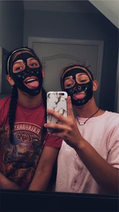 two people with black masks on their faces taking a selfie