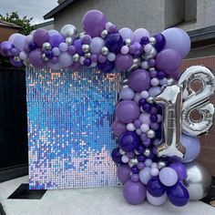 the balloon arch is decorated with purple and silver balloons, which spell out the number twenty nine