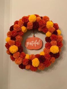 an orange and yellow wreath with the word grateful written on it hanging from a wall