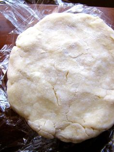 an uncooked pizza dough sitting on top of plastic wrap