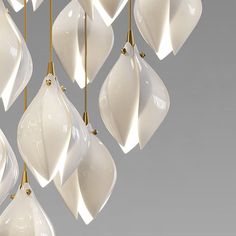 a bunch of hanging lights that are white and gold in the shape of flowers on a gray background