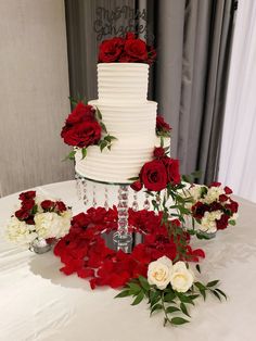 a white and red wedding cake surrounded by flowers