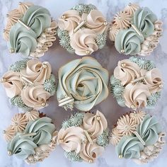 cupcakes decorated with frosting and flowers are arranged in a circle on a marble surface