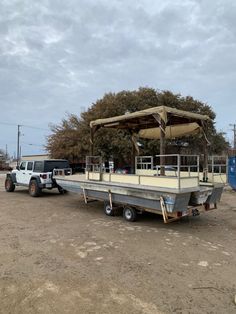 a truck is parked next to a boat on the trailer in front of a tree