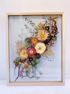 an arrangement of flowers in a wooden frame