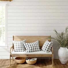 a wooden bench sitting on top of a hard wood floor next to a potted plant