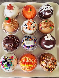 there are many cupcakes in the tray on the table, all decorated and ready to be eaten