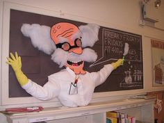 a man dressed as an old scientist in front of a chalkboard