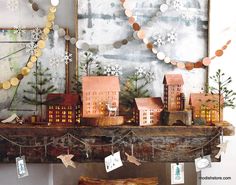 a fireplace mantle with christmas decorations and lights on it, along with small wooden houses