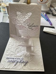 a card with a butterfly on it and the words believe in blue, sitting on top of a table