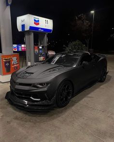 a chevrolet camaro is parked in front of a gas station