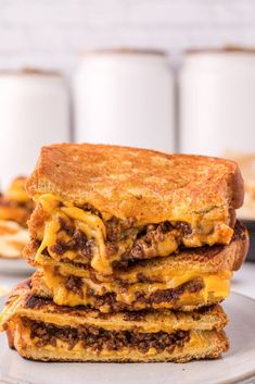 two grilled cheese sandwiches stacked on top of each other with coffee in the background