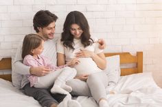 a man, woman and child sitting on a bed