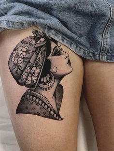 a woman's thigh with a tattoo design on the thighs and her head in a flowered hat