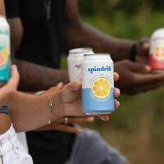 several people holding up cans of soda