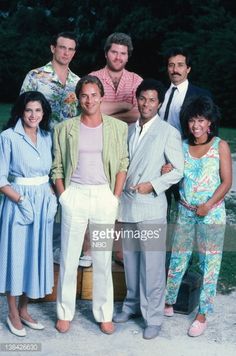 a group of people standing next to each other in front of trees and bushes, posing for the camera