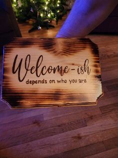 a wooden sign that says welcome - fish defends on who you are with a christmas tree in the background