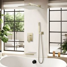 a bathroom with a large bathtub, shower head and plants in the window sill