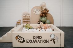 there is a dino excavation in the box with balloons and decorations on it's sides