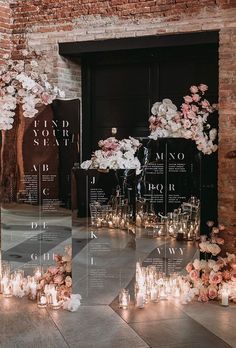 candles and flowers are arranged on the floor in front of a brick wall with glass doors