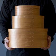 a person holding a stack of wooden boxes with writing on the bottom and sides in their hands