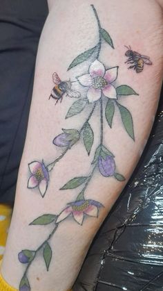 a close up of a person's leg with flowers and bees on it,