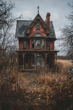 an old abandoned house sitting in the middle of a field with no leaves on it