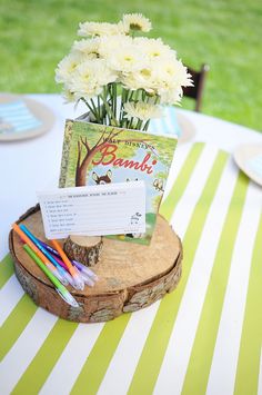 a table topped with a vase filled with white flowers and writing on top of a wooden slice