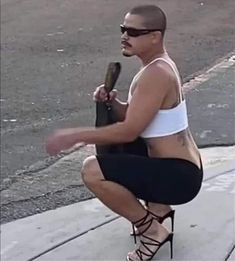 a man sitting on top of a skateboard next to a curb with his foot in the air