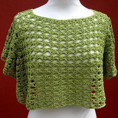 a white mannequin wearing a green crochet top on a red background