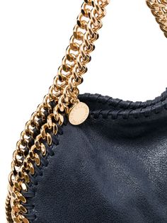 small Falabella tote bag from STELLA MCCARTNEY featuring indigo blue, gold-tone hardware, signature diamond-cut chain-link trim, adjustable detachable shoulder strap, two chain-link top handles, foldover top with magnetic fastening, logo charm and internal patch pocket. We've partnered with Good On You — an independent agency that rates how brands perform in relation to their impact on the planet, people and animals, with a multi-criteria rating simplified to a five points scale. In order to be Designer Top Handle Shoulder Bag With Chain Strap, Designer Shoulder Bag With Chain Strap And Top Handle, Luxury Shoulder Bag With Gold Chain, Designer Bag With Chain Strap, Designer Shoulder Bag With Chain Detail, Designer Shoulder Bag With Chain, Designer Leather Bag With Gold Chain, Designer Top Handle Bag With Chain, Chic Everyday Luxury Shoulder Bag With Chain