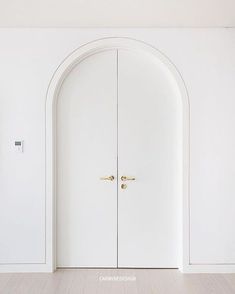 an arched doorway with two white doors in the center and wood floors on either side