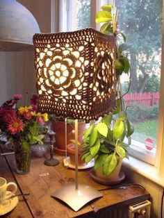 a lamp sitting on top of a wooden table next to a potted plant in front of a window