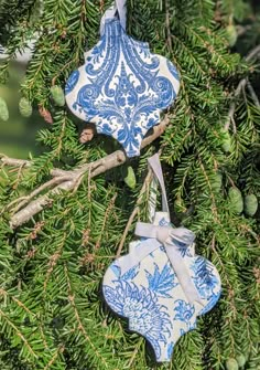 two blue and white ornaments hanging from a tree