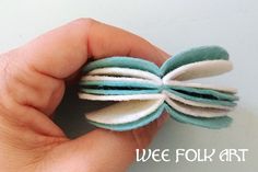 a hand holding a piece of felt with white and blue strips