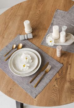 a wooden table topped with white plates and silverware