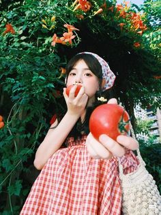 a woman in a red and white dress eating an apple