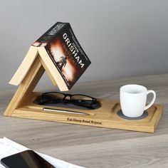 a wooden stand with a book, coffee cup and glasses on it