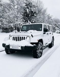 a white jeep parked on the side of a snow covered road with trees in the background